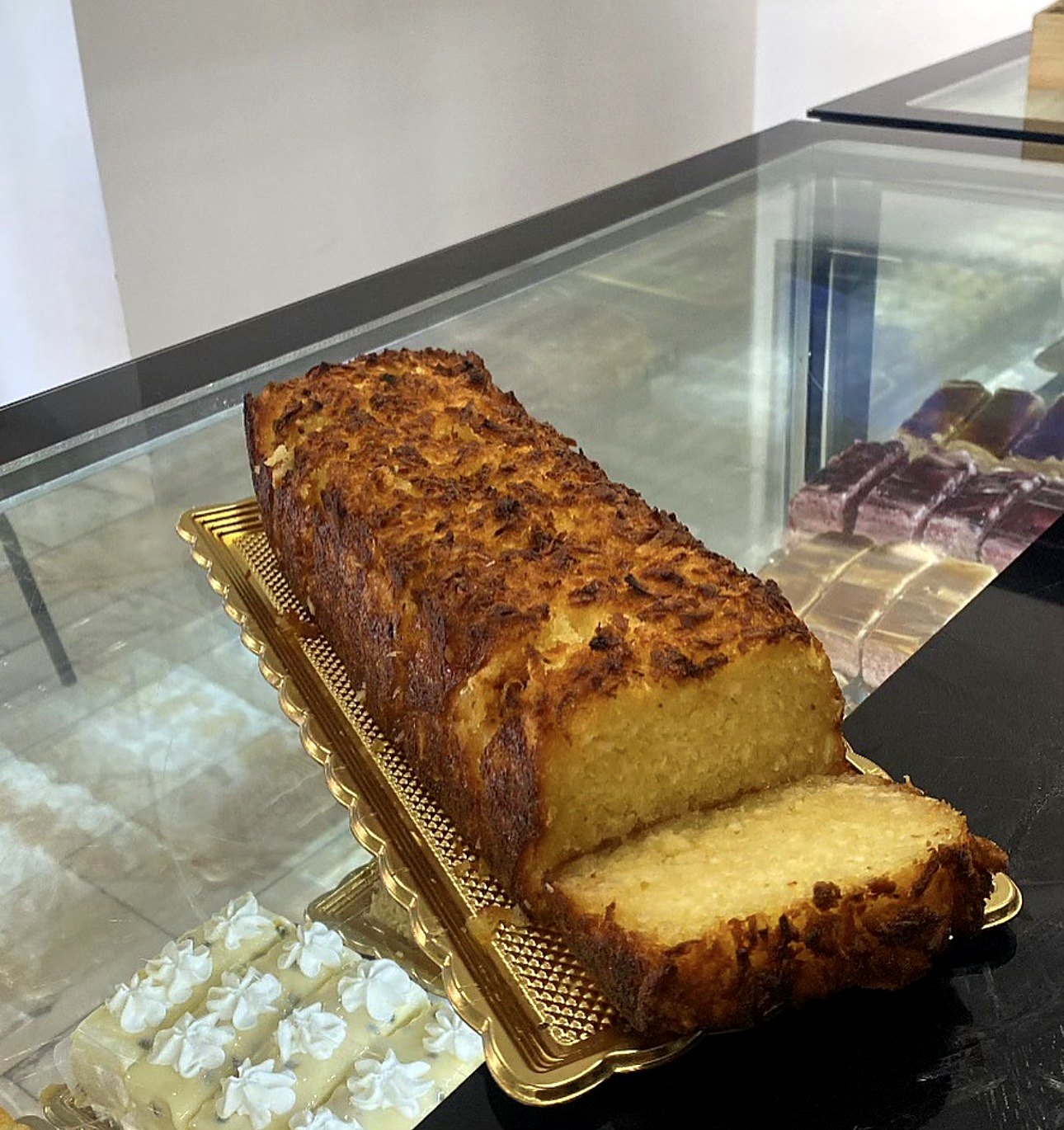 Bolo caseiro acabado de fatiar, com cobertura tostada, na montra da pastelaria